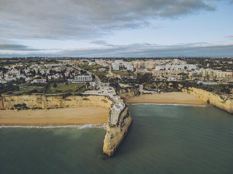 Aerial view of golden sands meeting turquoise waters near the cliffs of Praia da Rocha, where the ocean whispers tales of timeless beauty, Porches, Faro, Portugal.