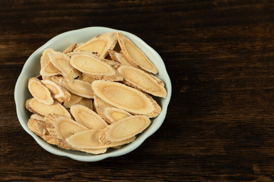 Astragalus Slices in Celadon Bowl on Wooden Table