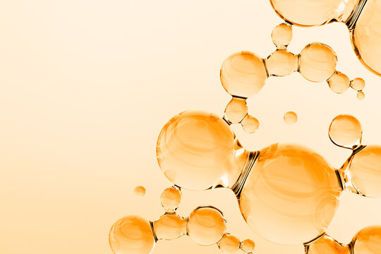 Abstract golden oil molecules floating on warm background. 3D render of luxury cosmetic serum or vitamin liquid with glossy transparent spheres, molecular structure, and copy space.
