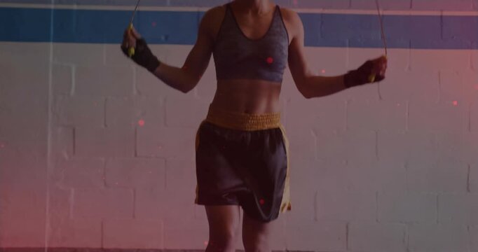 Female athlete flicking rope at feet, jumping and rotating arms while training cardio on mats