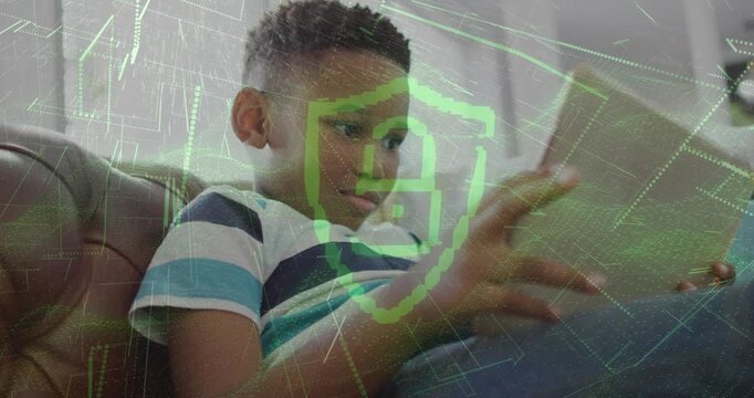 Boy on couch tapping tablet, causing green shield overlay pulsing and guarding tablet, showing tech