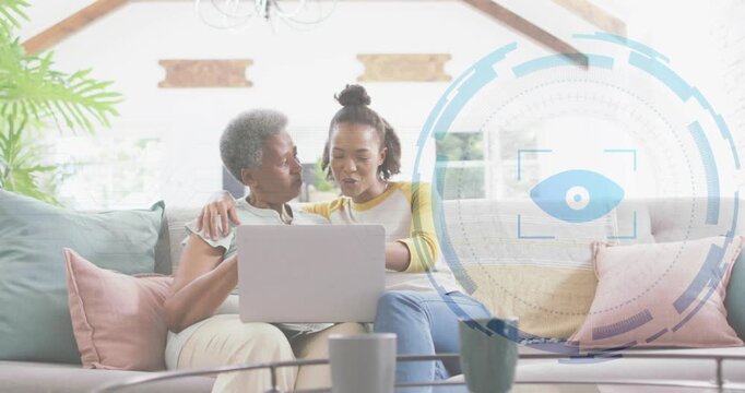 Mother and daughter on couch tapping laptop, causing blue HUD eye graphic to expand, exploring tech