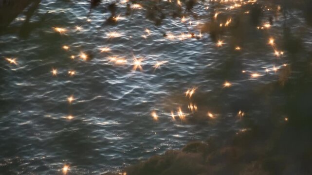 Calm sea waves creating a shimmering and sparkling water surface with the reflection of the sunset, ab01