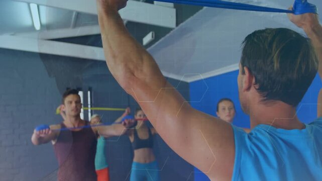Male coach starting overhead band pull leading fitness class mirroring for tone hex showing tension