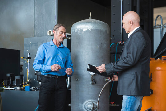 Two men looking at clipboard in factory