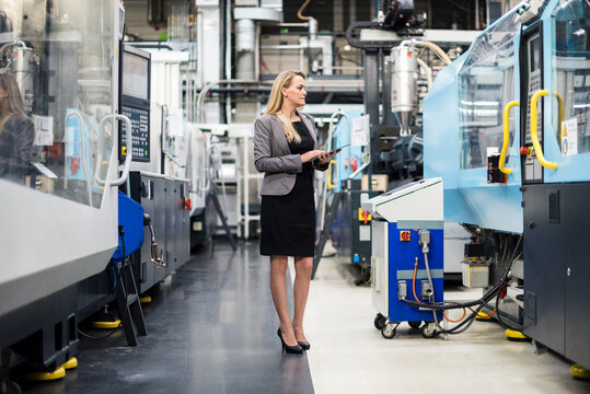 Woman using tablet at machine in factory shop floor