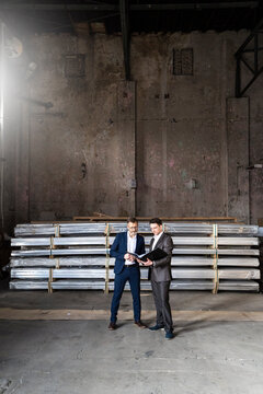 Two businessmen with folder talking in an old storehouse