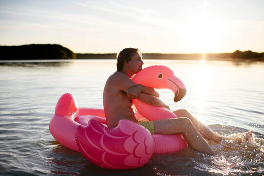 Young man with flamingo pool float on a lake