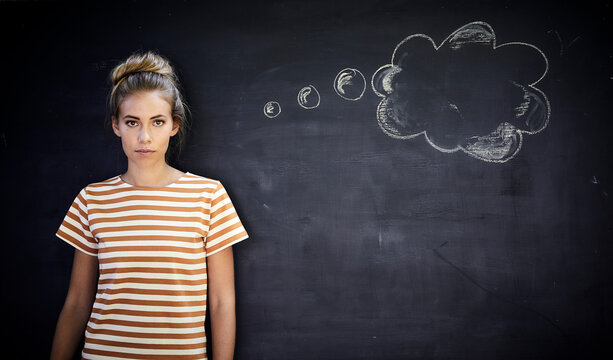 Pensive young woman standing in front of a blackboard next to a thought bubble