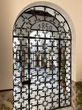 Ornate wrought iron gate with 1850 design protecting an old building's courtyard, showcasing traditional architecture and decorative security entry