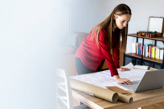Woman in office working on plan and laptop on table