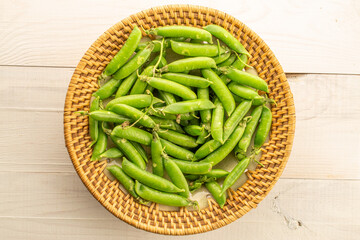 Green fresh peas on a wooden table, close-up. Top view.