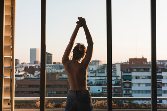 Rear view of topless young woman standing on balcony