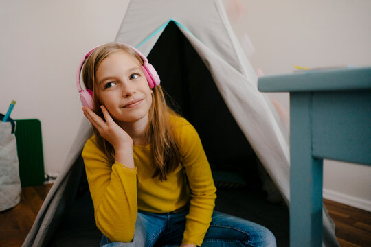 Smiling girl wearing headphones at home