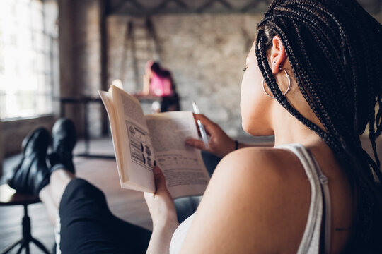 Young woman reading a book in loft office