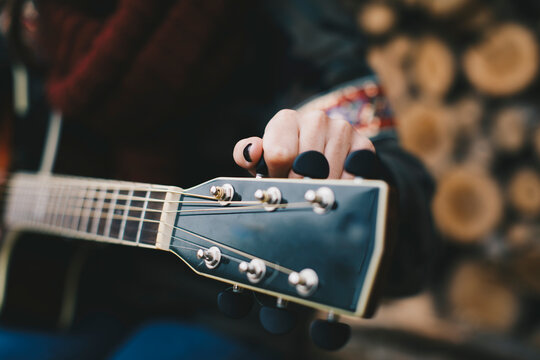 Young woman tuning guitar, close-up