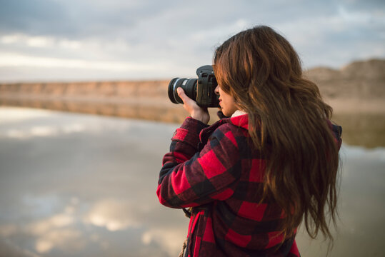 Young woman taking picture with camera on the beach