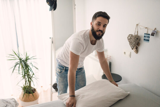 Young man making the bed at home