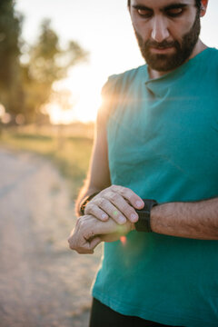 Young male athlete looking at smart watch while standing park
