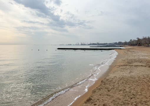 Sandy beach  along the Sea of Azov with industrial port in the distance, Donetsk Oblast, Mariupol, Ukraine