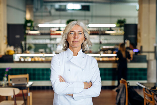 Proud business owner standing in her bistro with arms crossed