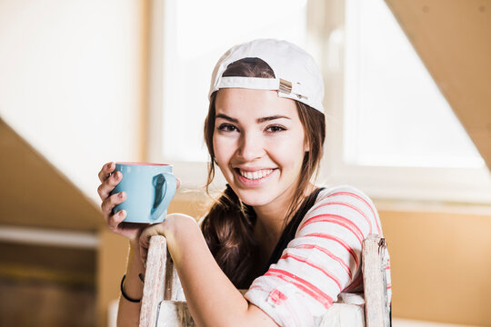 Young woman on construction site holding cup of coffee