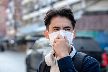 Naklejka premium Air pollution quality of dust PM 2.5 is toxic and dangerous to health. Man having a sore throat wearing Protection mask unhealthy air pollution dust smoke in an urban city and smog with bad weather.