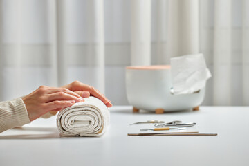 Woman enjoying a self-care beauty routine with a hand on a rolled white towel
