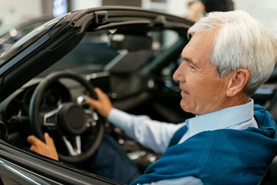 Senior man testing convertible in car dealership