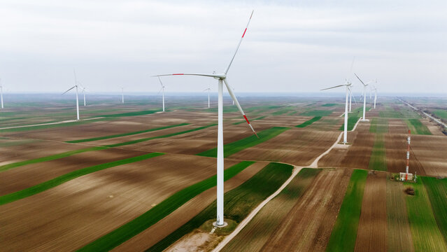 Aerial view of wind turbines standing tall against a backdrop of patterned fields, Alibunar, Vojvodina, Serbia.