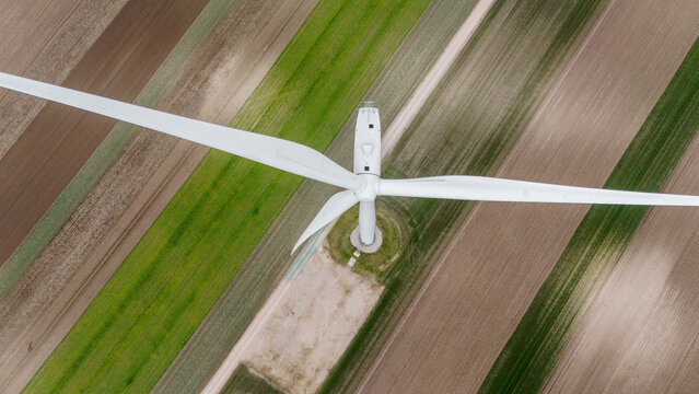 Aerial view of a towering wind turbine standing tall amidst a patchwork of agricultural fields, its blades reaching towards the sky, Alibunar, Vojvodina, Serbia.