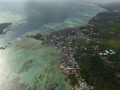 Aerial view of the town sprawling along the coast where the azure sea meets the vibrant green forests, Karimunjawa, Central Java, Indonesia.
