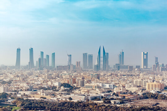 View of a skyline punctuated by modern skyscrapers and buildings, reflecting the city's economic growth under a blue sky, Manama, Capital Governorate, Bahrain.