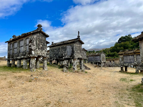 View of weathered stone Espigueiros stand as silent witnesses on the dry earth under a blue sky, Lindoso, Viana do Castelo District, Portugal.