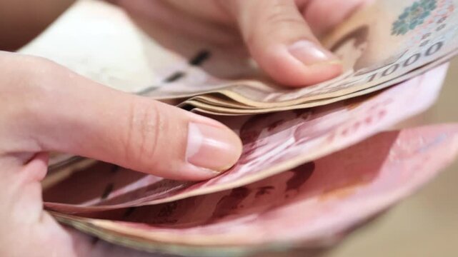 Hands counting banknotes, Thai money close-up. symbolizing finance, cash flow, savings, expenses, spending, and budgeting management