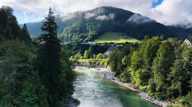 Cinematic aerial drone shot of the emerald Traun River flowing through a forested alpine valley near Bad Ischl in the Salzkammergut region of Austria. Scenic European alpine landscape.