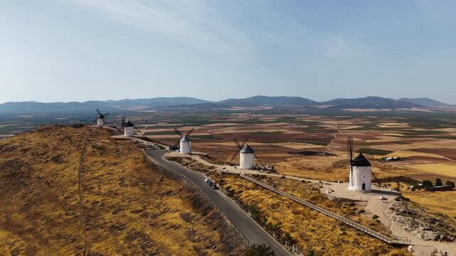 Aerial drone view of historic windmills on a hill near Consuegra overlooking the vast plains of La Mancha in Castilla-La Mancha, Spain. Famous landscape associated with the story of Don Quixote.