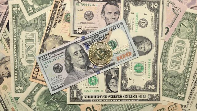 Bitcoin rotates in slow motion against a backdrop of dollar bills. Bitcoin and US currency as background or illustration and copy space for text
