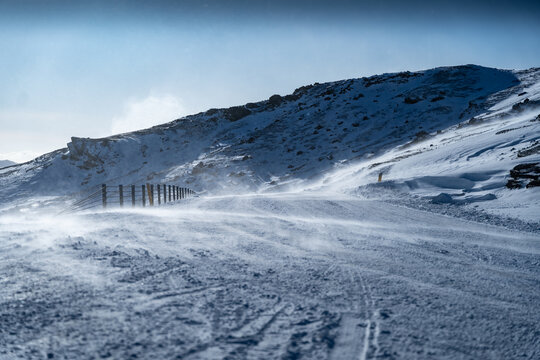 View of a snow-covered landscape where the wind whips across the ground, creating swirling patterns and a sense of isolation, Kleifarvatn, Grindavikurbaer, Iceland.