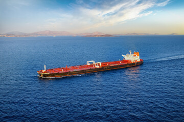 Aerial view of a heavy loaded crude oil tanker traveling off the coast during sunset time