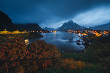 Stunning fall scenery in the Lofoten Islands. Iconic red rorbu cabins nestled between rocky coastlines and dark arctic waters during the golden hour. Travel Norway. © PawelUchorczak