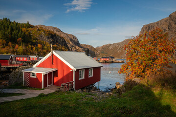 Historic architecture in Nusfjord, Lofoten. Peaceful autumn atmosphere, wooden cabins reflecting in the dark water surrounded by majestic mountains