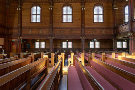 View of the warm wooden interior of Olden Old Church with rows of pews and windows casting light, creating a serene and inviting atmosphere, Olden, Vestland, Norway.