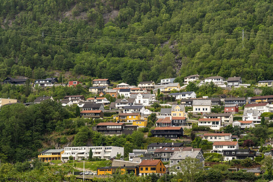 View of colorful houses nestled against a verdant hillside, a charming Norwegian village scene under a soft sky, a blend of nature and architecture, Odda, Vestland, Norway.