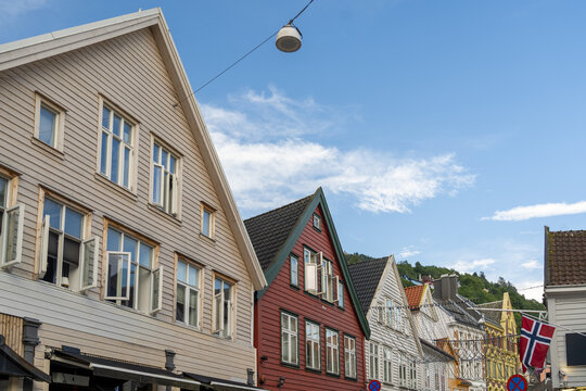 View of colorful wooden houses with triangular roofs stand proudly against a clear blue sky, a testament to timeless architecture, Bergen, Vestland, Norway.