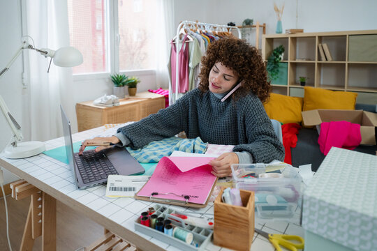 Entrepreneur multitasking in home office with laptop and fabric samples