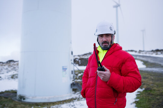 Worker with radio at wind turbine outdoors in winter maintenance scene