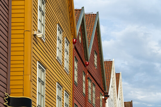 View of colorful wooden facades with triangular roofs create a captivating architectural rhythm against a soft sky, Bryggen, Bergen, Norway.