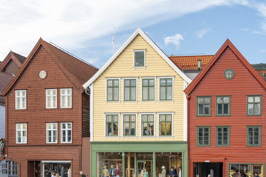 View of vibrant wooden buildings in a row with gabled roofs and colorful facades, a blend of history and commerce, Bryggen, Bergen, Norway.