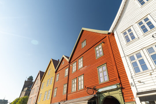 View of vibrant, wooden buildings stand tall against a clear blue sky, their colorful facades a testament to history and charm, Bryggen, Bergen, Norway.